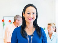 Asian ethnic woman smiling at the camera with two caucasians in the background.