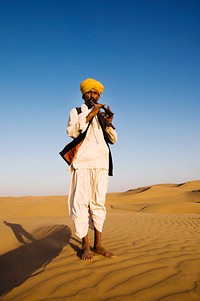 Indian man playing wind pipe in the desert
