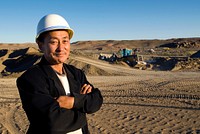 Construction man with arms crossed standing and smiling in a construction site.