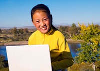 Mongolian girl with laptop by lake.