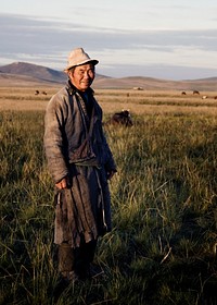 Mongolian milking man standing in a scenic view of the field.