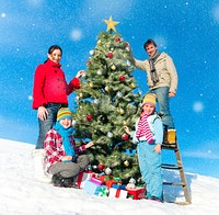 Family posing for camera while decorating christmas trees.