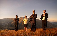 Business team meditating on Top of the mountains.