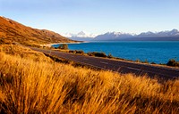 Country road with amazing scenery of lake and a mountain range.