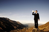 Businessman shouting on the top of the mountain.