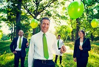 Group of business people holding balloons in the forest.
