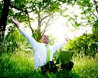 Businessman sitting in a forest with his laptop.