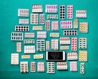 A bunch of pills tablet packets on the table with a mobile