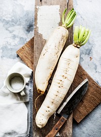 Aerial view of daikon radish on wooden cutboard with knife