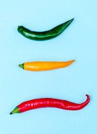 Aerial view of fresh red green yellow chili peppers on blue background