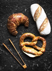 Croissant pretzel and baguette with wooden tongs