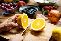 Hands using knife cut half of a fresh orange