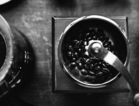 Closeup of coffee grinder on wooden table grayscale