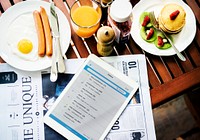 Closeup of breakfast with digital tablet and newspaper