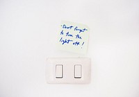Electric light switch with reminder note on white wall