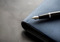 Macro of fountain pen on black notepad