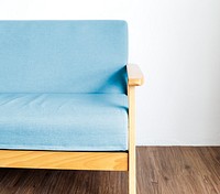 Closeup of blue sofa on wooden floor with white wall