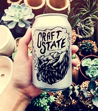 Hand holding craft state beer can with houseplants background