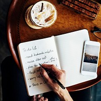 Closeup aerial view of hand writing to do list at cafe