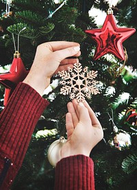 Putting a snowflake decoration on the Christmas tree