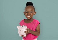 Cute little girl smiling awkwardly holding a piggy bank