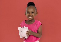 Cute little girl smiling awkwardly holding a piggy bank