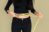 Young woman measuring her waist with tape