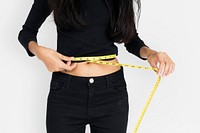 Young woman measuring her waist with tape