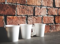Paper coffee cups by the brick wall