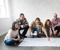 Group of people looking at a big sheet of paper on the floor