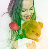 A woman is holding rose and bear doll.