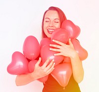 A caucasian woman is happy wtih a heart shape balloon.