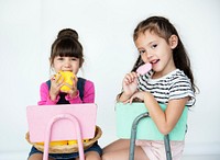 Elementary Age Schoolgirls Sitting on the Chair on the White Background