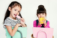 Elementary Age Schoolgirls Sitting on the Chair on the White Background