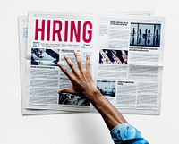 Hand reaching to grab newspaper for hiring job announcement