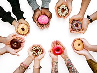 Diverse hands holding deliciously colorful donuts