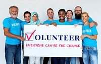 Group of volunteer people smiling and holding charity banner