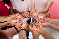 Group of hands holding pink ribbon for breast cancer awareness