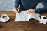 Closeup of hands drawing banners badges in drawing book on wooden table