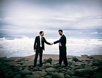 Businessmen shaking hands with stormy ocean background.