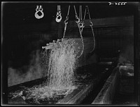 Conversion. Copper and brass processing. Pickling lengths of copper water tube in a brass and copper mill. After annealing, or softening by heat to reduce brittleness and allow further drawing, tubes are "pickled" in a sulphuric acid solution to remove oxide and scale that result from the anneal. Bundles of the tubes are picked up by electric cranes and transported from the pickle to a rinse bath of water. The tubes are then returned to the drawbench for re-drawing down to smaller diameters. Chase Copper and Brass Company, Euclid, Ohio. Sourced from the Library of Congress.