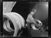 Conversion. Copper and brass processing. Strip copper and brass is usually passed through rolls many times before the desired thickness is obtained. This is placing a roll of strip into a feed box at the entrance to the rolls for intermediate rolling. Chase Copper and Brass Company, Euclid, Ohio. Sourced from the Library of Congress.