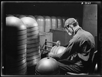 Conversion. Beverage containers to aviation oxygen cylinders. After the circumferential straps are welded to the cylindrical portion, in the metal division of a large Eastern rubber factory, rough edges and accumulated weld scale are removed by a skilled workman. The twin rotary brushes, shown above, do their work on the inside and outside of the cylinder in the same operation. This process is required in the manufacture of shatterproof oxygen cylinders for high altitude flying. Firestone, Akron, Ohio. Sourced from the Library of Congress.