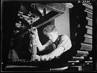 A track for an Army halftrac car nears completion as curing plates nuts are removed with an air pressure wrench on the trimming rack of a Midwest rubber plant. Goodrich, Akron, Ohio. Sourced from the Library of Congress.