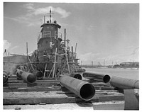 Industrial salvage. Marine iron and steel scrap. Steel for war production is saved by reconditioning the wooden tug "Raymond" at the Seabrook, Louisiana yard of the Standard Dredging Corporation. To avoid replacing it by a new steel tug, general repairs are made on this vessel needed on war projects. Pontoon pipes are in the foreground. Standard Dredging Corporation. Sourced from the Library of Congress.