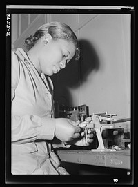 Production. Aircraft engines. Reconditioning used spark plugs for reuse in testing airplane motors, Mighnon Gunn operates this small testing machine with speed and precision although she was new to the job two months ago. A former domestic worker, this young woman is now a willing and efficient war worker, one of many women who are relieving labor shortages in war industries throughout the country. Melrose Park, Buick plant. Sourced from the Library of Congress.