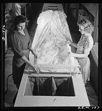 Production. Parachute making. As these two girls thread shroud cords through the material, these yards of silk become more nearly recognizable as one of the parachutes turned out by this Eastern plant. Pioneer Parachute Company, Manchester, Connecticut. Sourced from the Library of Congress.