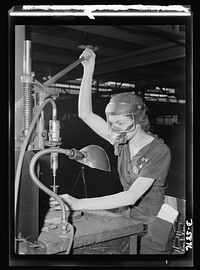 Women in industry. Aircraft motor workers. A million dollar baby, not in terms of money but in her value to Uncle Sam, twenty-one-year-old Eunice Hancock, erstwhile five-and-ten-cent store employee, operates a compressed-air grinder in a Midwest aircraft motor plant. With no previous experience, Eunice quickly mastered the techniques of her war job and today is turning out motor parts with speed and skill. Note protective mask and visor, two vital safety accessories. Sourced from the Library of Congress.