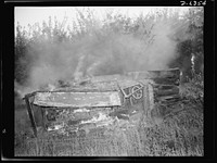 Automobile salvage. Before the torch men, shear men, and press operators go to work on an old automobile, all wooden parts, upholstery, oil, grease and other unusable and inflammable material are removed by burning. Sourced from the Library of Congress.