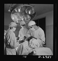 Nurse training. An important phase of every nurse's training is assisting at operations. In this emergency tracheotomy, the doctor is inserting a tube into the trachea as a nurse stands ready to hand him an instrument. Sourced from the Library of Congress.